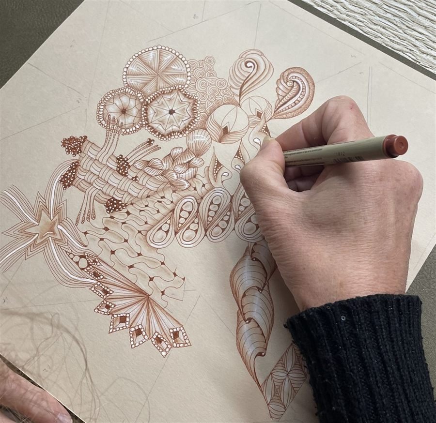 La main de Nathalie Guillemet traçant un zendala au feutre sanguine sur papier